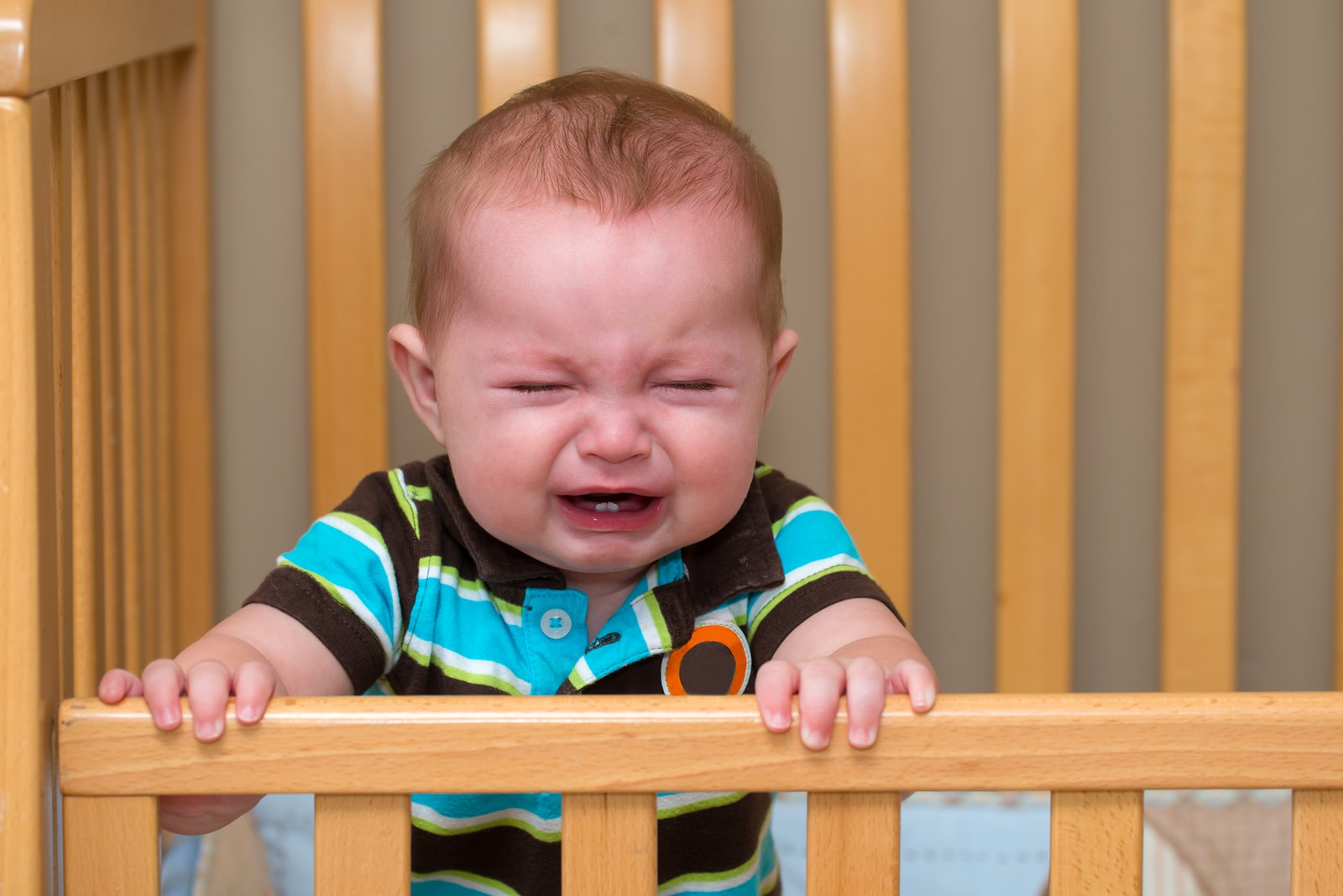 Crying Unhappy Baby Standing In His Crib