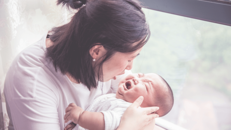 mom comforting crying baby looking in mouth for tongue tie